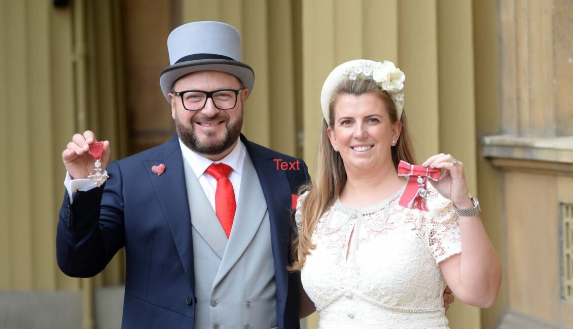 Two people holding MBE medals.